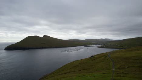 Atlantic-Ocean-salmon-farm-off-coast-of-Vagar-Island-by-Sandavagur-village,-aerial-pedestal-establish