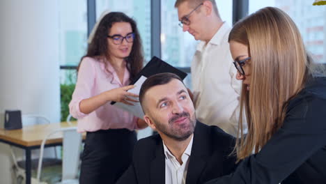 businessman sitting at computer and listening to his female employee talking. couple employees standing and talking about the charts at the backdrop.