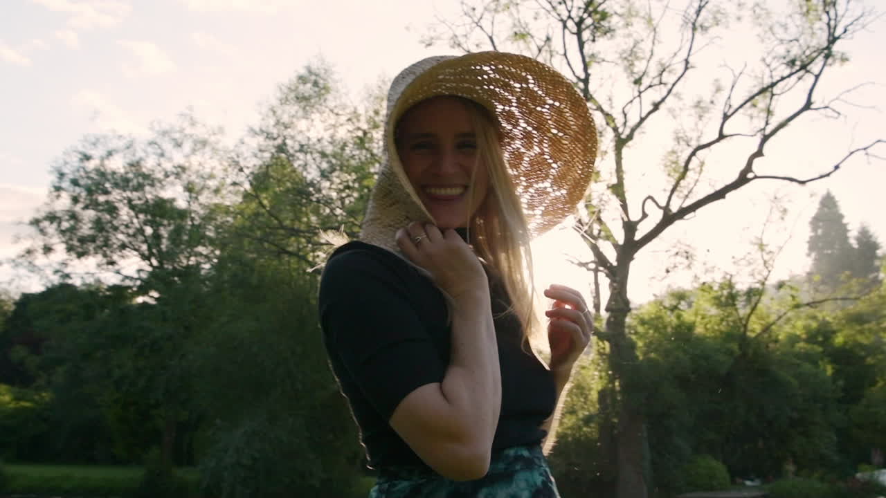 Cute young woman smiling out of pure happiness holding straw hat with light rays