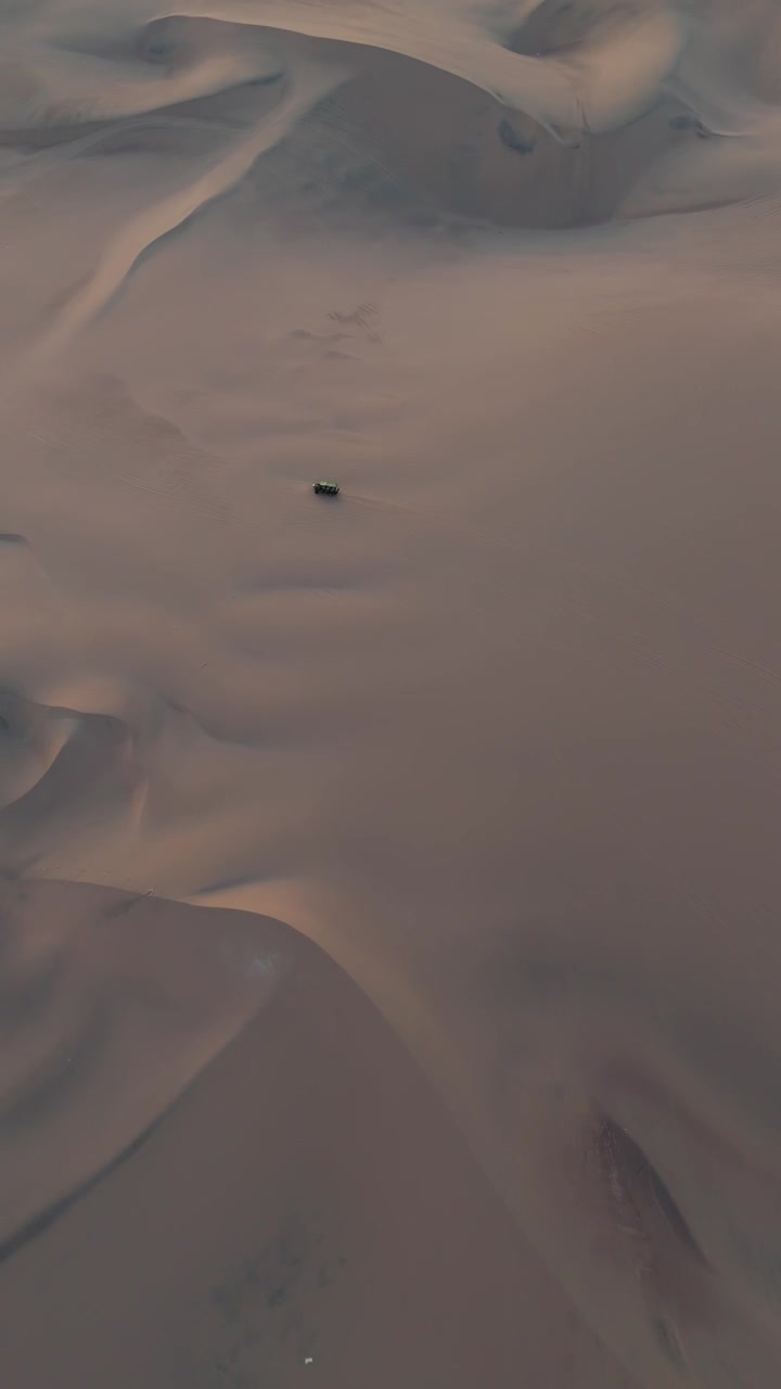 Ripresa verticale con drone di un dune buggy fuoristrada che attraversa le dune di sabbia nel deserto peruviano, le dune di sabbia di Huacachina
