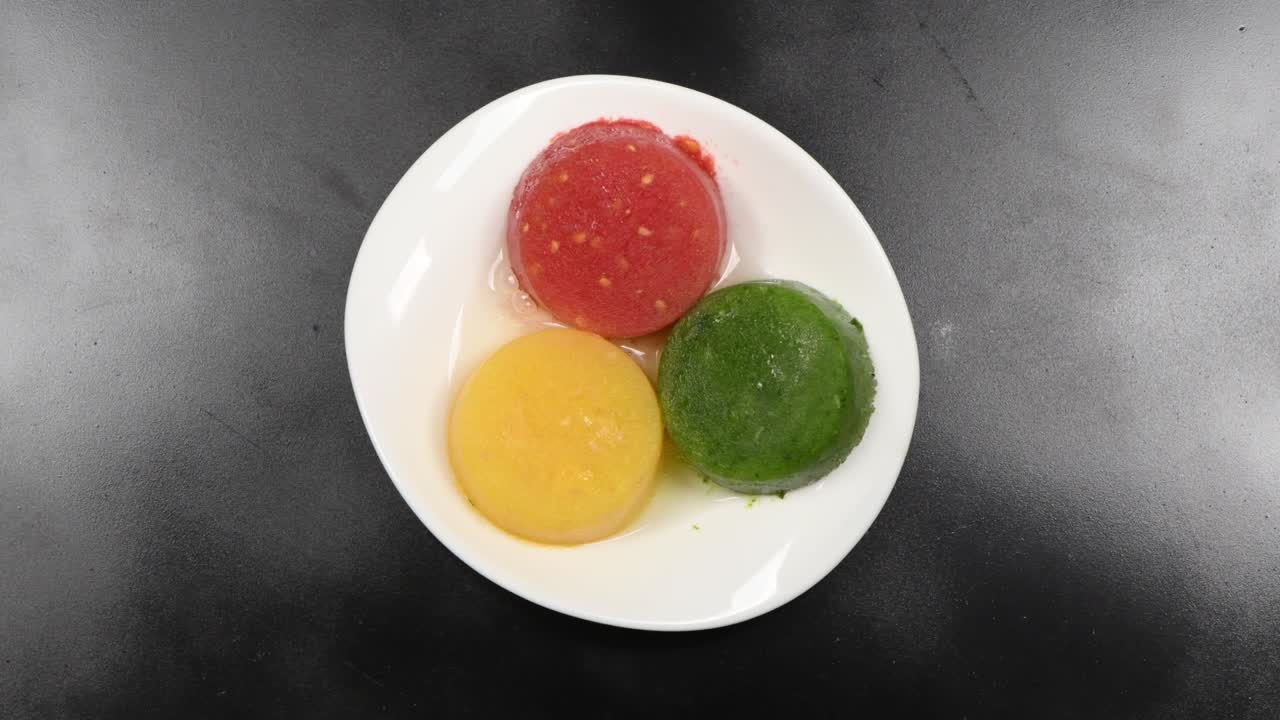 framboesa de melocotón congelado y batido de kiwi en un plato blanco. plato sobre un fondo negro. vista superior. movimiento en bucle. rotación 360.