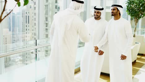 arabic businessmen wearing traditional dress meeting shaking hands