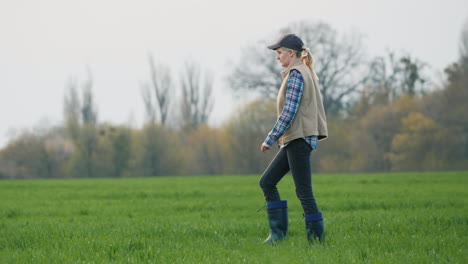 a woman farmer goes to her field where winter wheat has sprouted