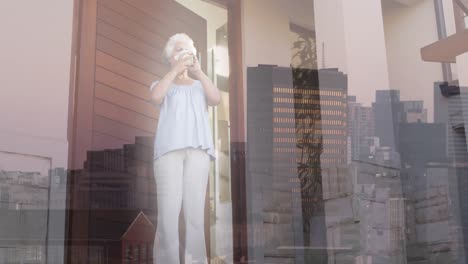 Animation-of-african-american-senior-woman-drinking-coffee-over-cityscape