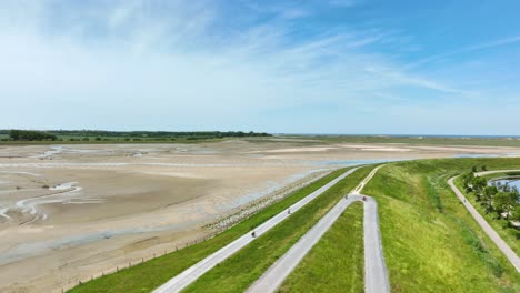 Flight-above-bikers-on-promenade-along-dry-muddy-dutch-river-bed