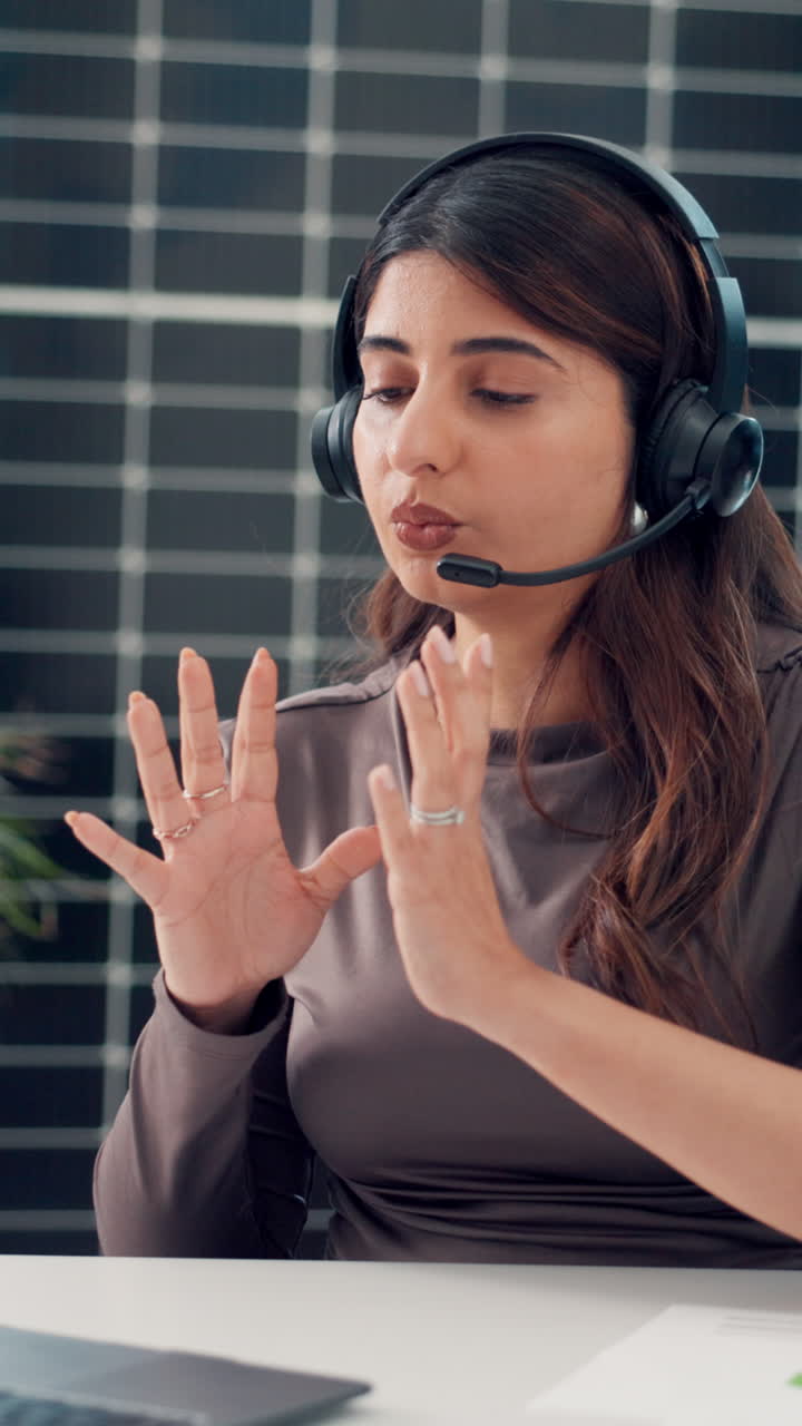 Mujer joven con auriculares hablando y gesticulando durante una videollamada