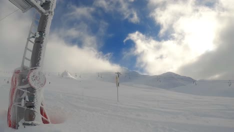 sunny day button lift ride: pov footage capturing skiers descending with chairlift in background