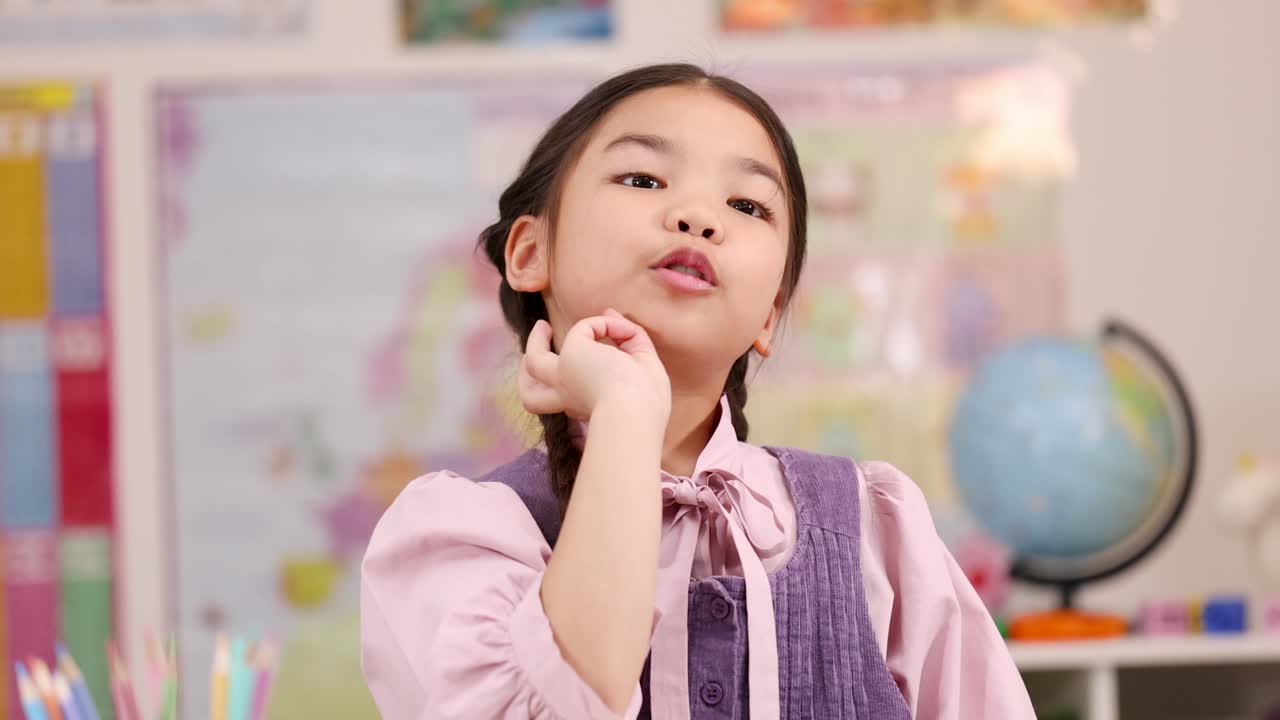 Asian girl counts one, two, three on fingers in bright classroom, front-facing camera, natural lighting