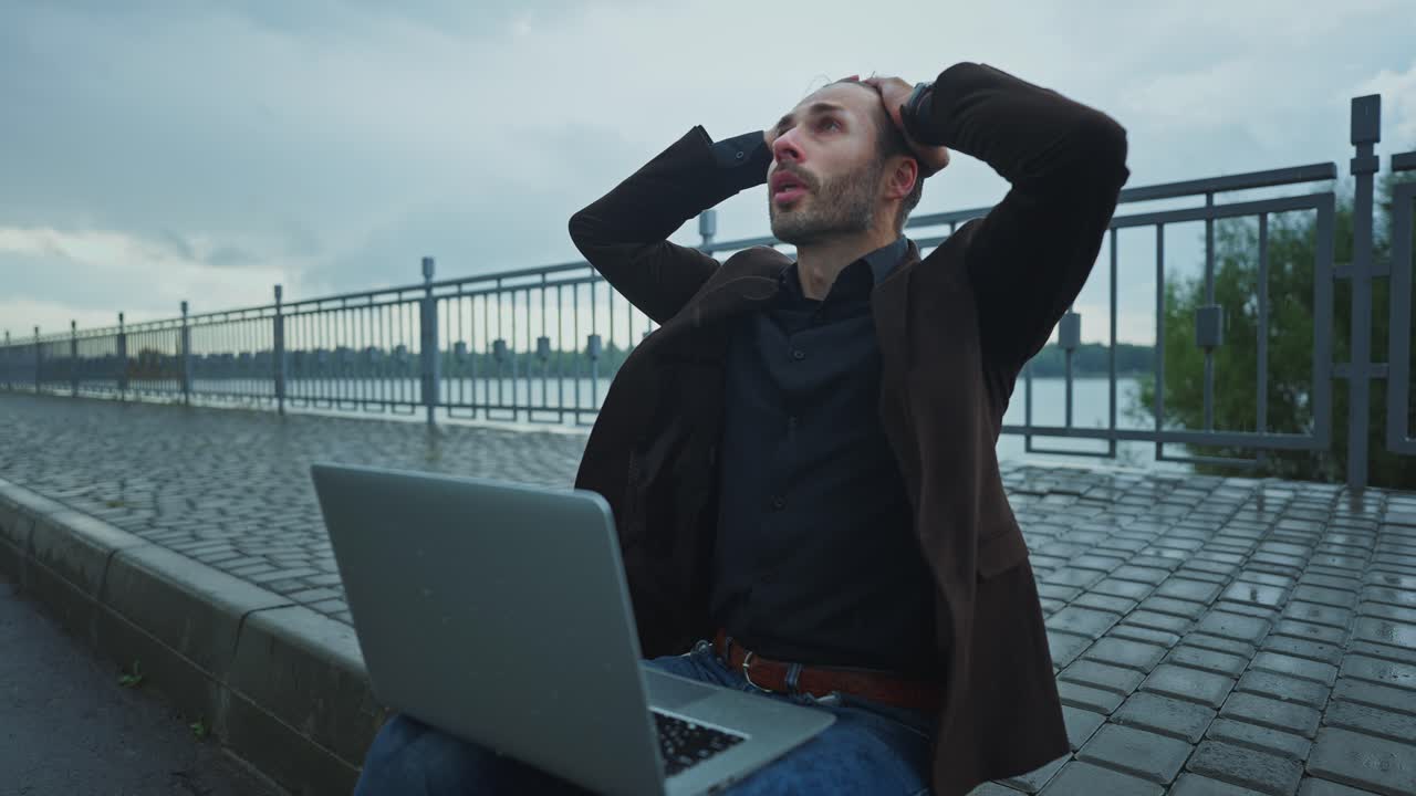 Uomo d'affari stressato che lavora all'aperto sotto la pioggia