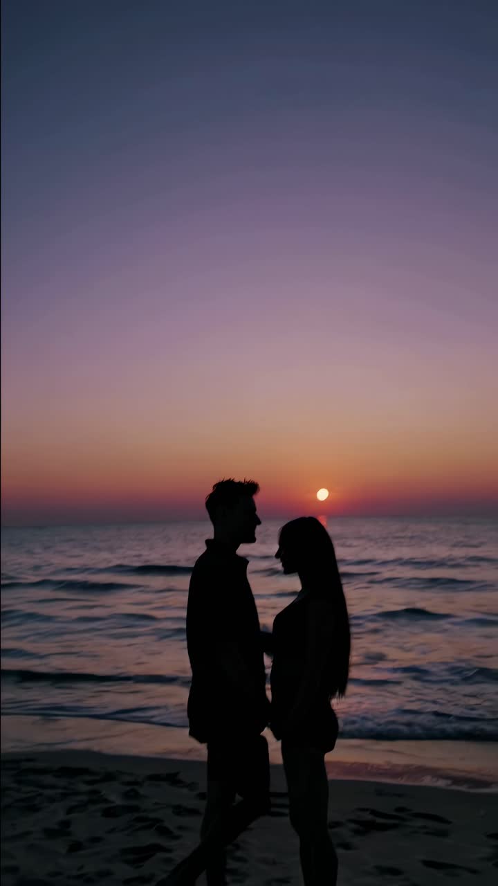 Silhouette of a couple at sunset on a beach, captured from a low angle