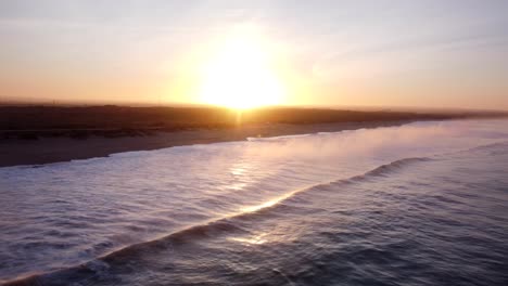 Sobrevuelo-Aéreo-Del-Agua-Del-Océano-Atlántico-Con-Pequeñas-Olas-Que-Llegan-A-La-Playa-De-Supertubos-En-Peniches-Al-Atardecer