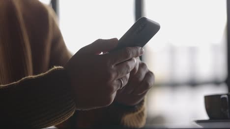 side view of man hands with watch using mobile phone while working at laptop. male fingers typing and tapping on smartphone. texting and scrolling. slow motion.