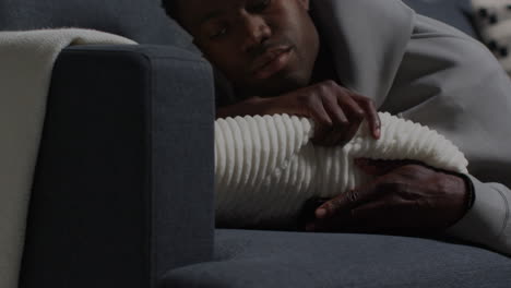 close up of unhappy and depressed young man lying on sofa at home looking at mobile phone