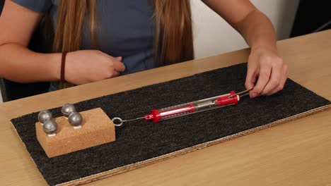 a person uses a spring scale to measure friction and force on a weighted block across a carpeted surface