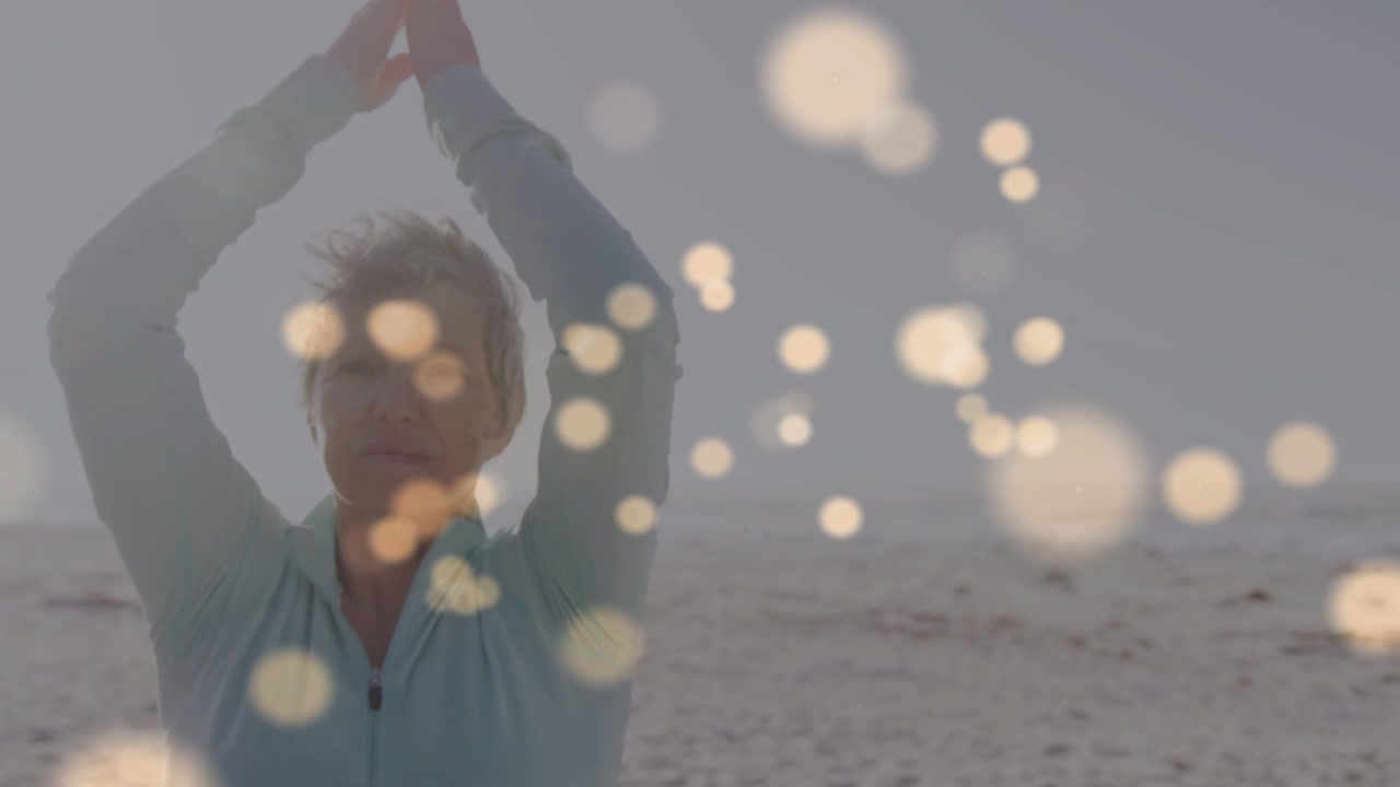 Woman raising arms starting stretch on beach, moving to seated meditation with bokeh for health
