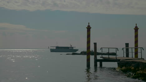 Handheld-shot-of-scenic-dock-and-a-passenger-boat-slowly-flowing-on-Garda-Lake,-Italy