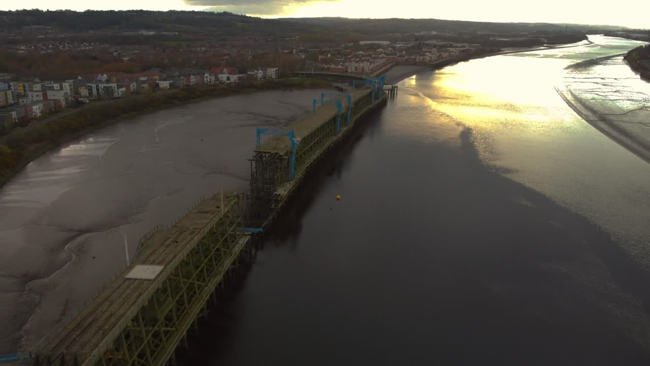Aerial View of Old Pier at Sunset Over River and Town