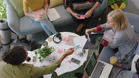 Jóvenes-Ingenieros-Que-Desarrollan-Software-De-Aplicaciones-De-Fitness-Utilizando-Una-Tableta-Digital-Para-Intercambiar-Ideas-Sobre-Soluciones-De-Diseño-En-La-Reunión-De-La-Oficina-De-Inicio-En-La-Vista-Superior