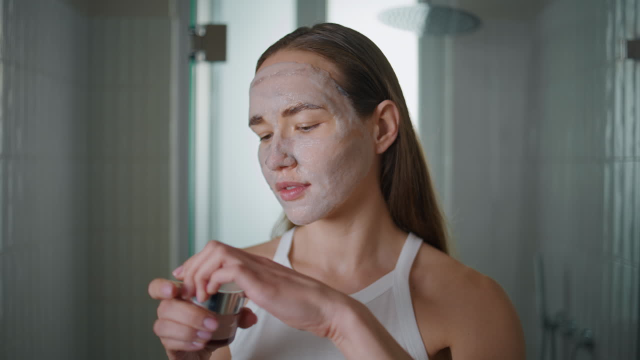 Woman checking skincare product enjoying home spa closeup. Girl with face mask