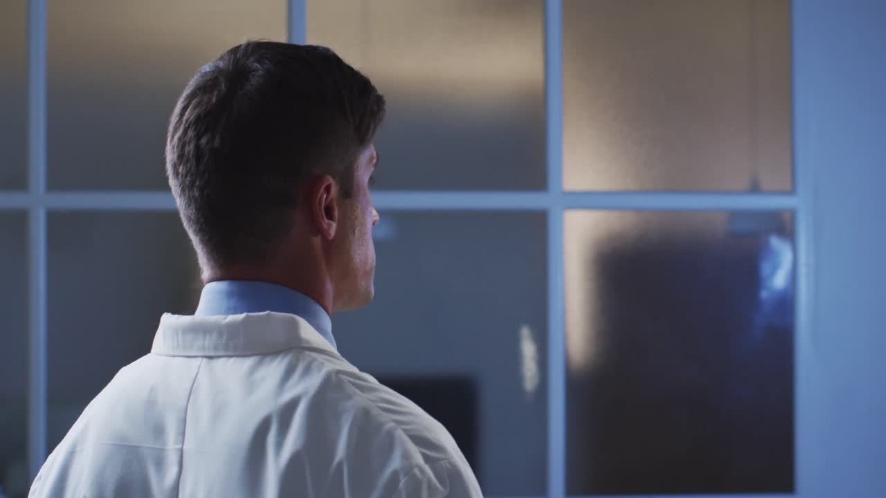 가상 디지털 인터페이스를 사용하여 실험실 코트를 입은 백인 남성 의사의 뒷면