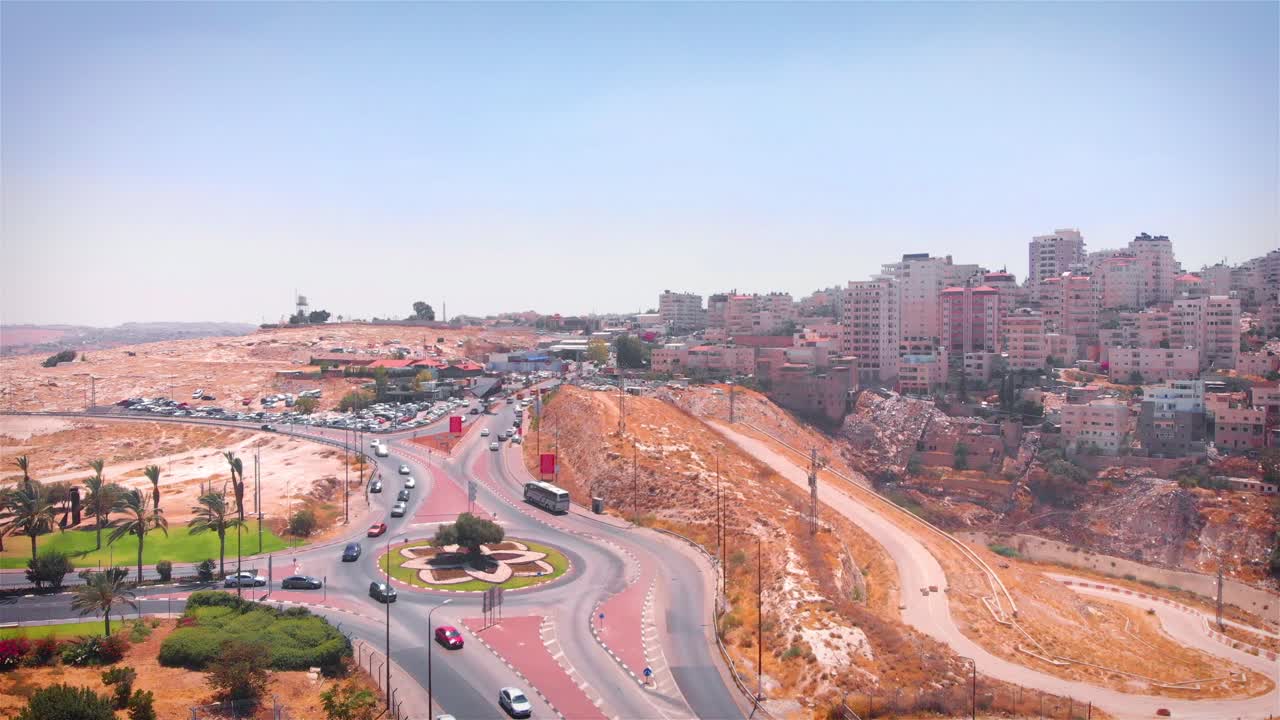 Aerial view of a city with a busy roundabout and hillside buildings