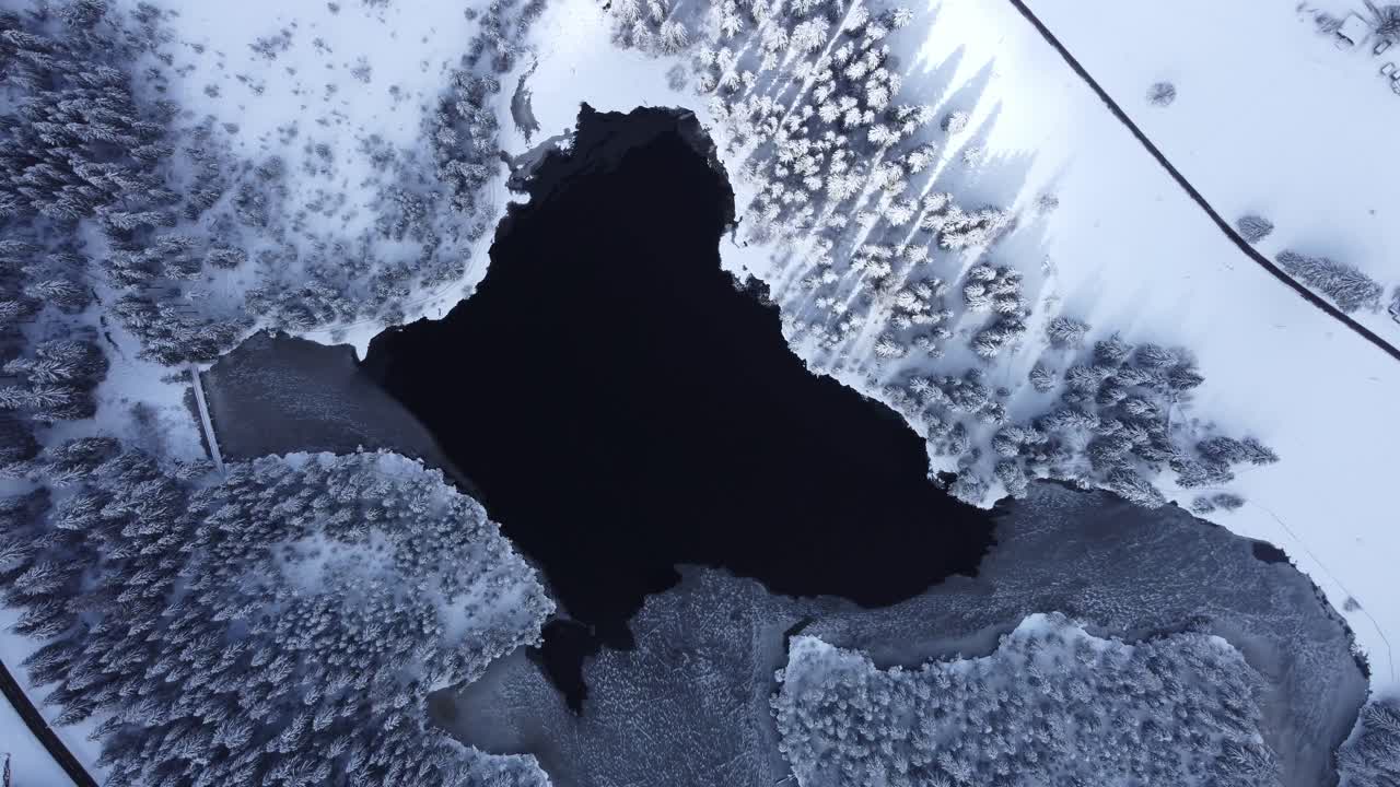 Frozen ice lake with snow surrounded landscape from high altitude filmed with drone in winter wonderland Switzerland at the Etang de la Gruere