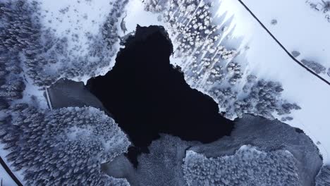 frozen ice lake with snow surrounded landscape from high altitude filmed with drone in winter wonderland switzerland at the etang de la gruere
