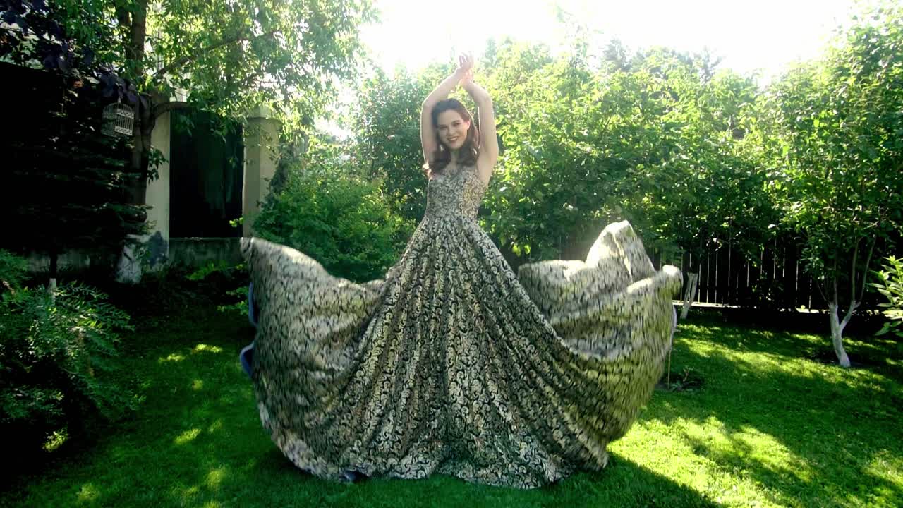 Woman in a gold and black embroidered gown in a garden