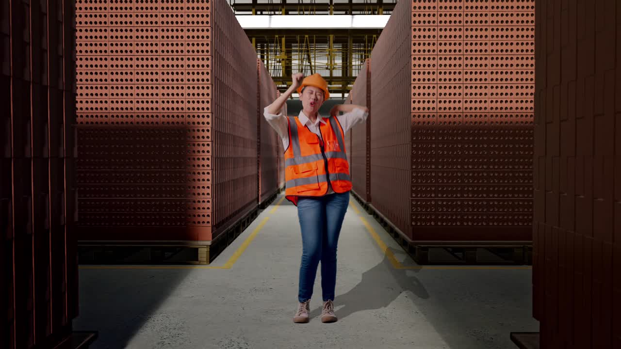 Full Body Of Asian Female Engineer With Safety Helmet Screaming Goal And Dancing Celebrating With Red Brick Packed in Stacks Are Stored