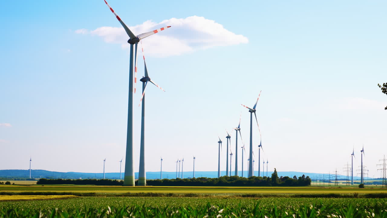 Lots of windmills rotate in the wind. Low angle view at the wind turbines located in the rural area.