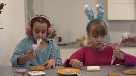 two beautiful sisters decorate and eat delicious cakes at a wooden table