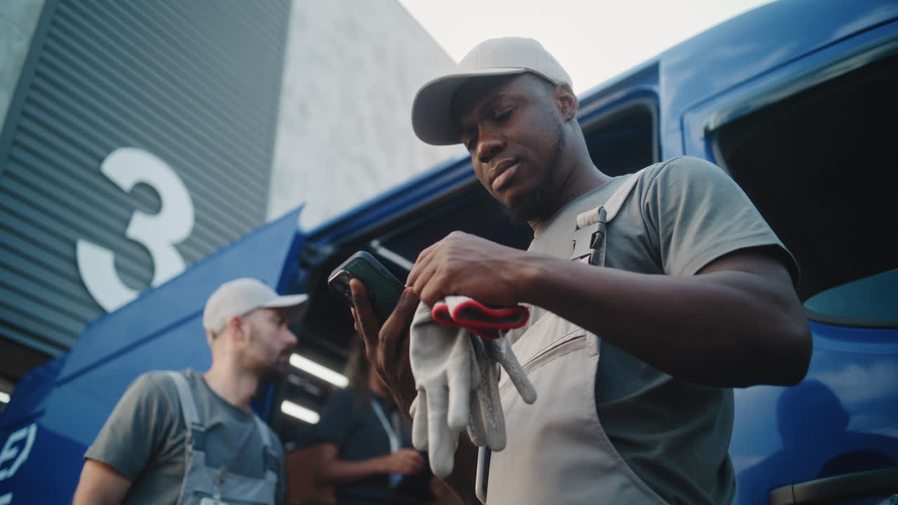 Logistics workers managing operations with a smartphone near a delivery van