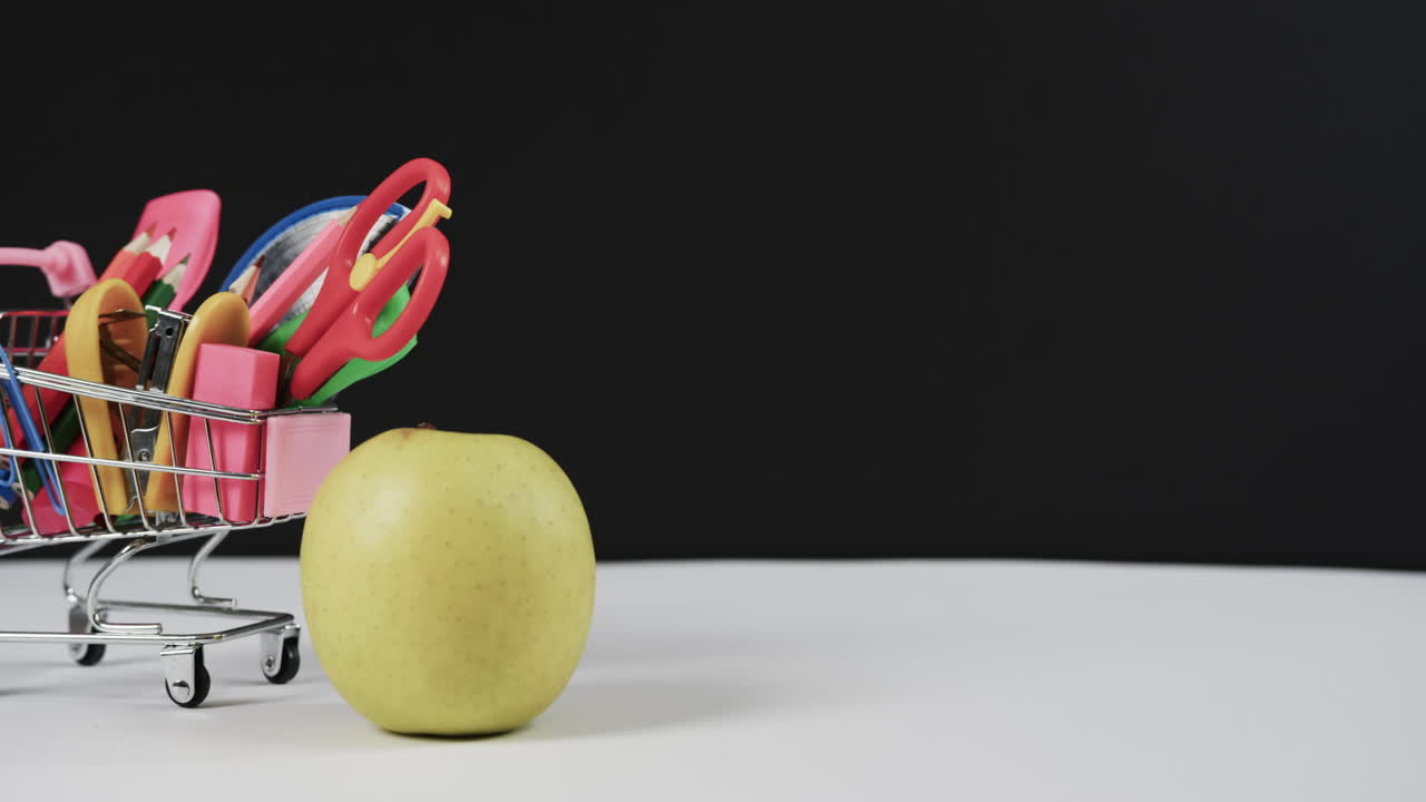 cerrar el carrito de compras con artículos escolares y manzana con espacio de copia en fondo negro