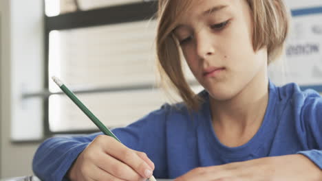in school, focused student writing with pencil in classroom, concentrating on task