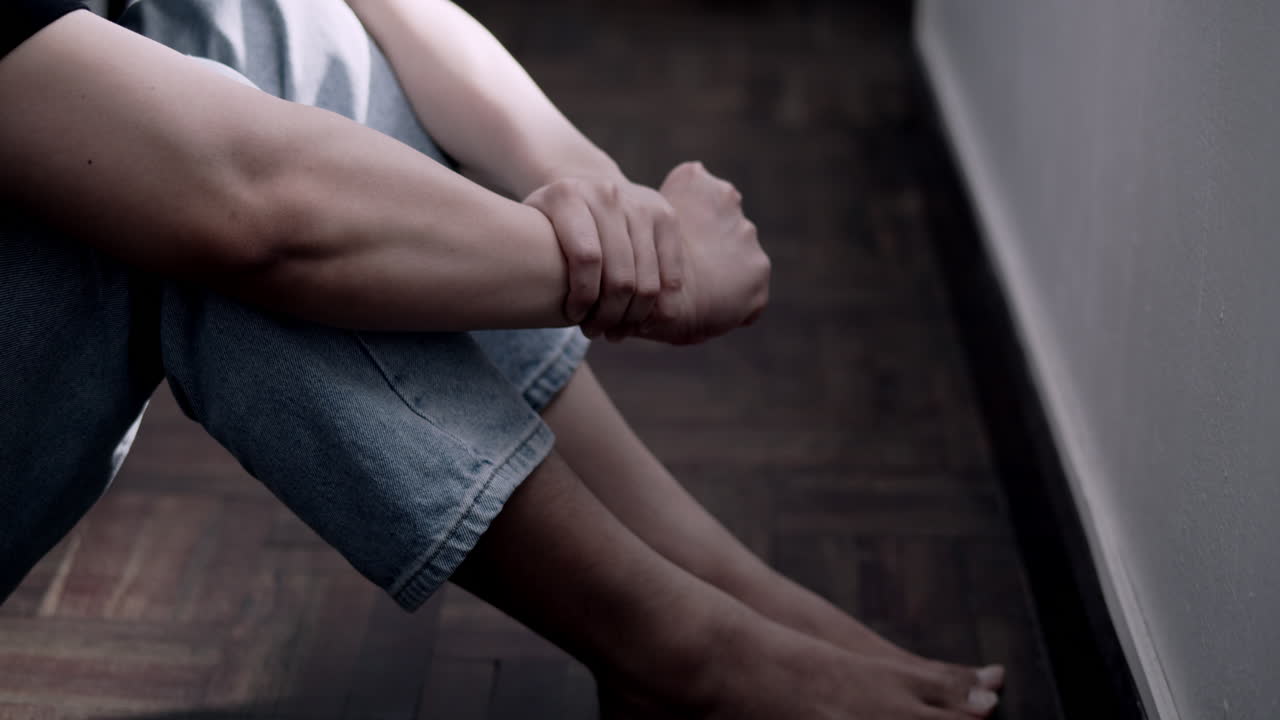 una persona se enfrenta a luchas emocionales en un espacio interior débilmente iluminado que refleja batallas personales.