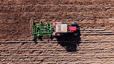 cinematic top view of tractor tilling textured earth in warm european spring sun