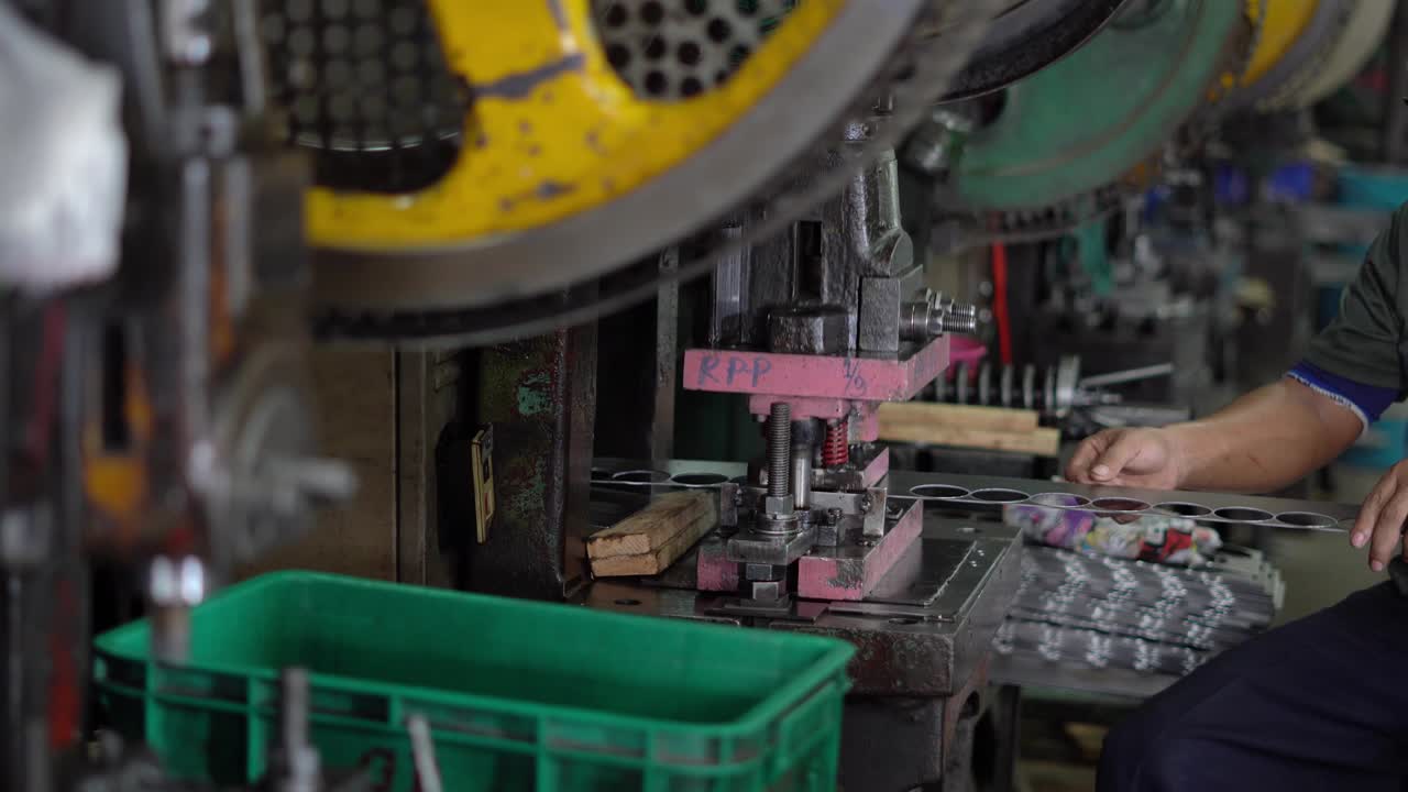 la máquina está trabajando estampando un círculo de una larga placa de acero, controlada por el trabajador y no tiene protección de seguridad.