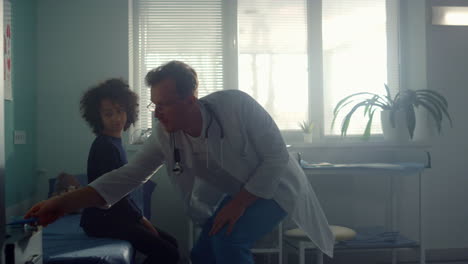pediatrician checking visual reflex african american teen girl in clinic office.