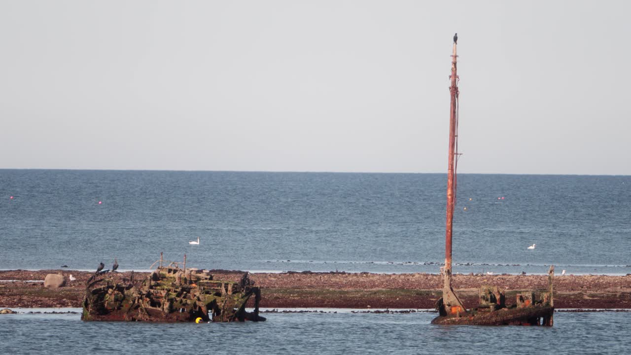 Cinematic view of the SS Kaffir shipwreck off Ayr, Scotland. Rusted hull and mast sit in shallow waters, offering a haunting glimpse of maritime history and coastal decay