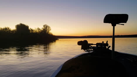 Colorful-Sun-Rise-in-Bass-Fishing-Boat-on-Calm-Beautiful-Lake,-Ripples-in-the-Water-and-Trees-in-the-Background,-Yellow-and-Purple