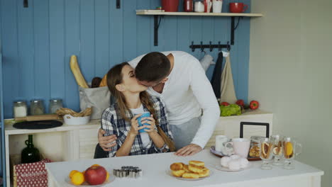 una pareja besándose en la cocina.