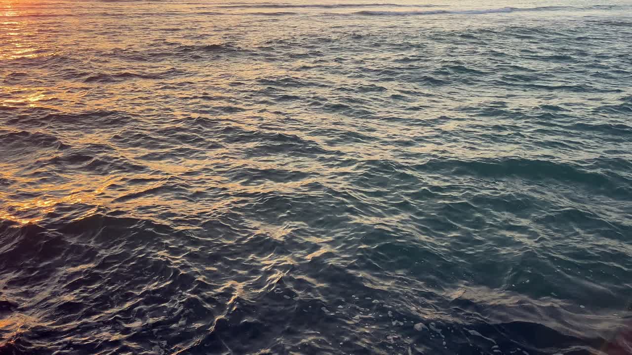 water clip with waves, sea, ocean, river, lake or lagoon with wind and the reflection of the sunset colors.