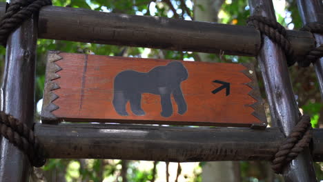 Gorilla-enclosure,-directional-wooden-signage-at-zoo,-panning-shot-left-to-right