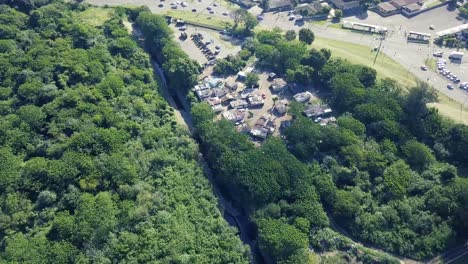 Drone-Volando-Hacia-Un-Campamento-De-Ocupantes-Ilegales-Rodeado-De-árboles-Tupidos