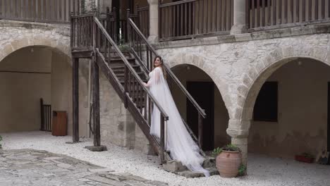 una novia posa para las fotos en los escalones de una villa de adoquines griega