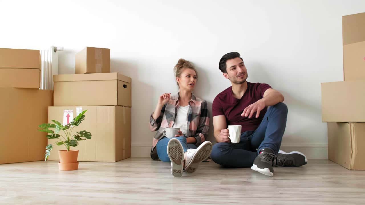 una joven pareja tomando un descanso mientras se muda de casa