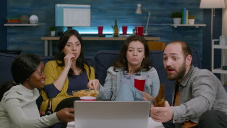 multiracial friends relaxing on couch while watching comedy film