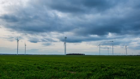 Time-lapse-of-a-windmill-farm,-in-country-cultivated-fields,-on-a-cloudy-evening