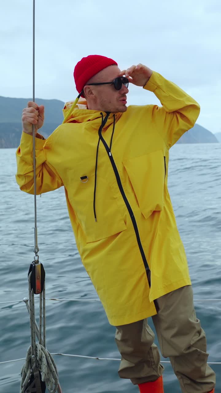 Hombre aventurero con impermeable amarillo en un velero