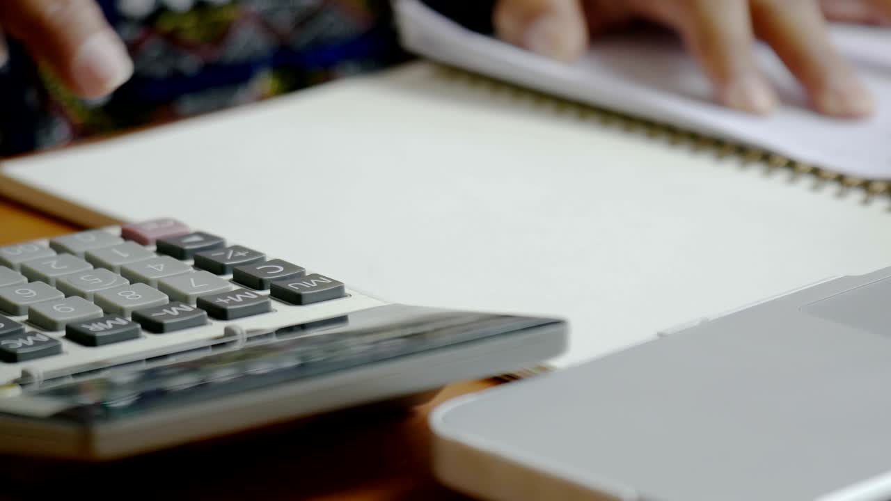 4k mujer usando calculador de análisis de datos financieros. mano con pluma en la calculadora.